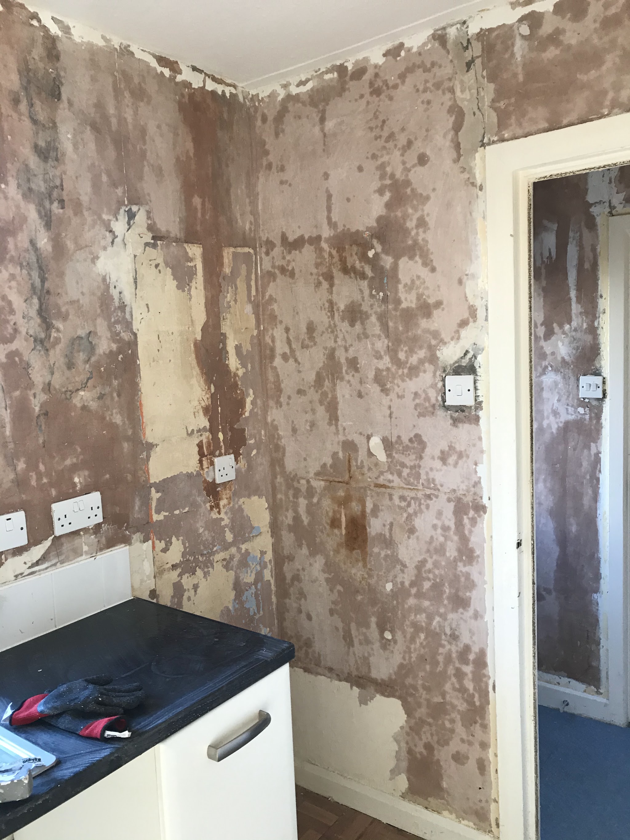 Kitchen walls stripped back to patchy bare plaster before decorating