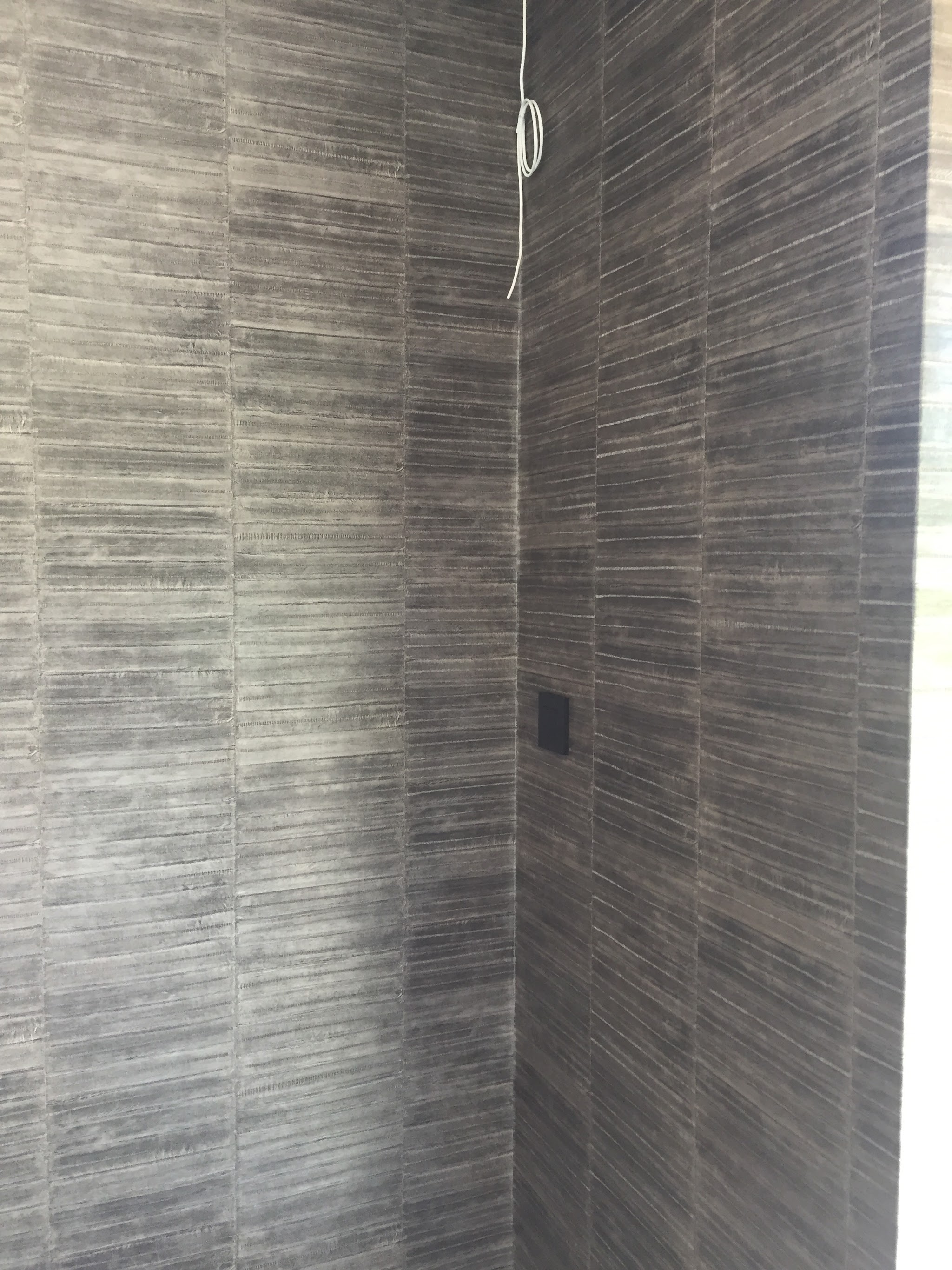 Close-up of a charcoal and grey textured feature wallpaper hung in a corner