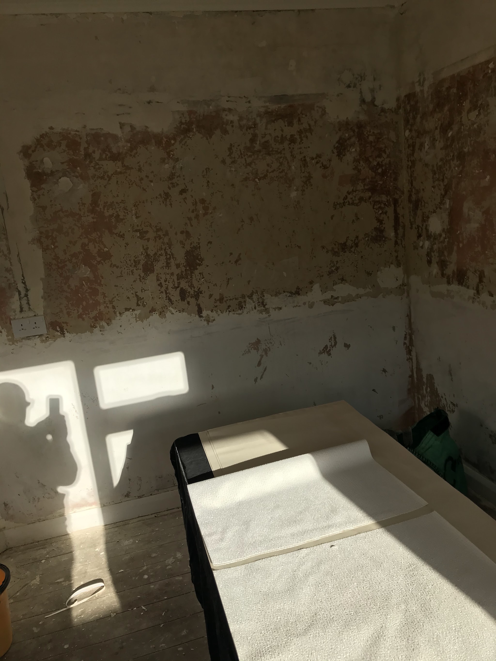 Bedroom walls stripped, with a pasting table and a roll of lining paper