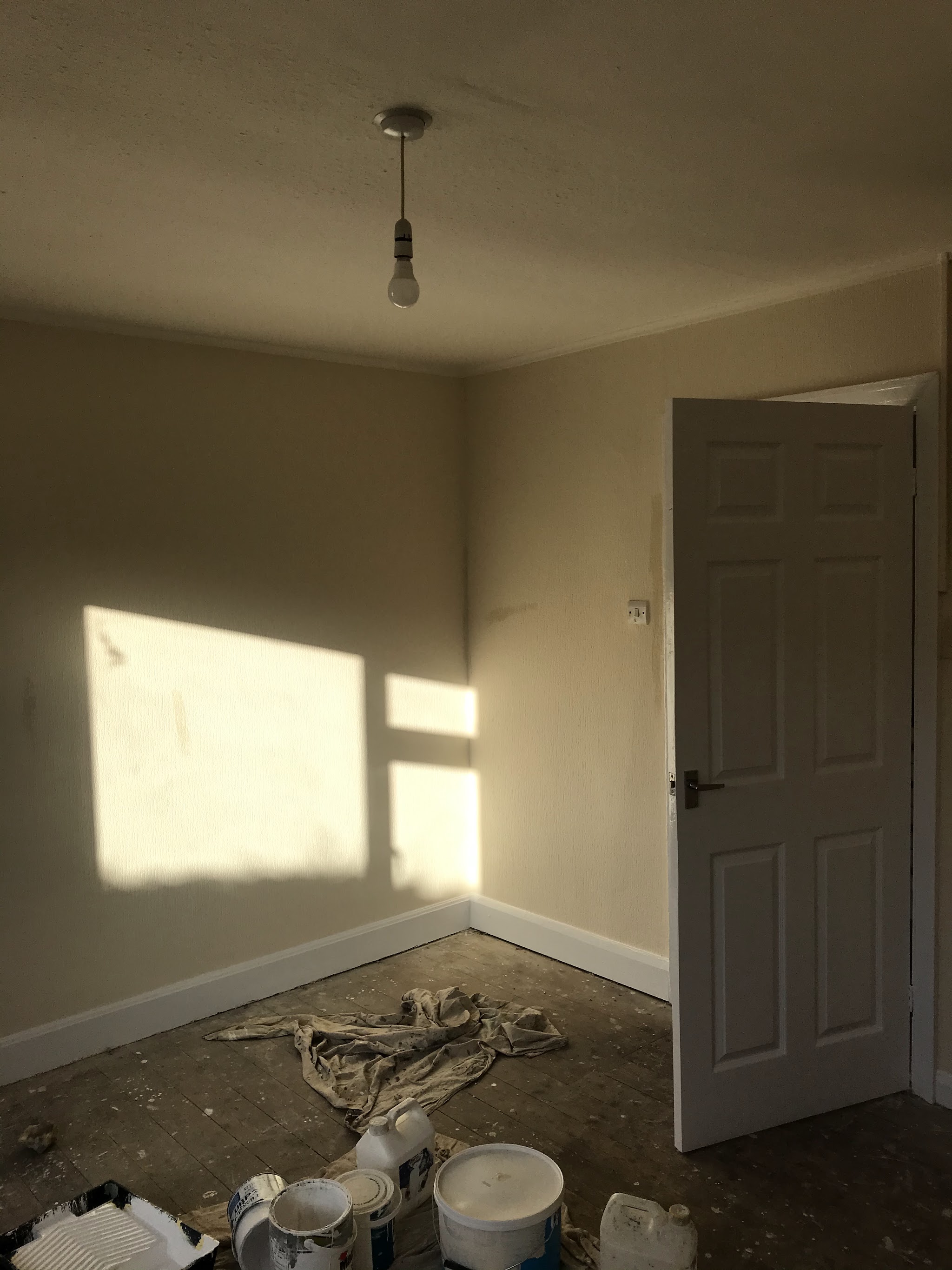 Finished bedroom in soft cream with white skirting and a white panel door