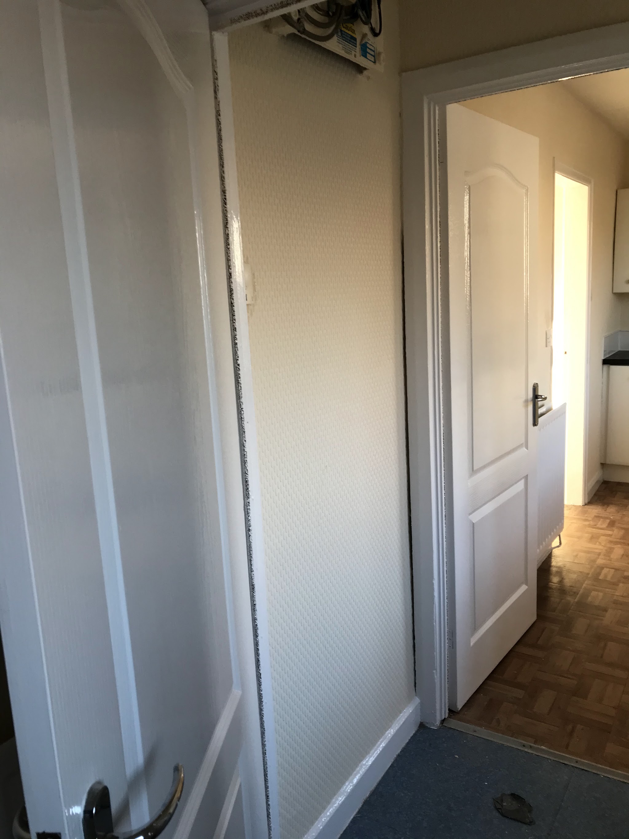 Finished hallway with a white textured wall, white door and frame