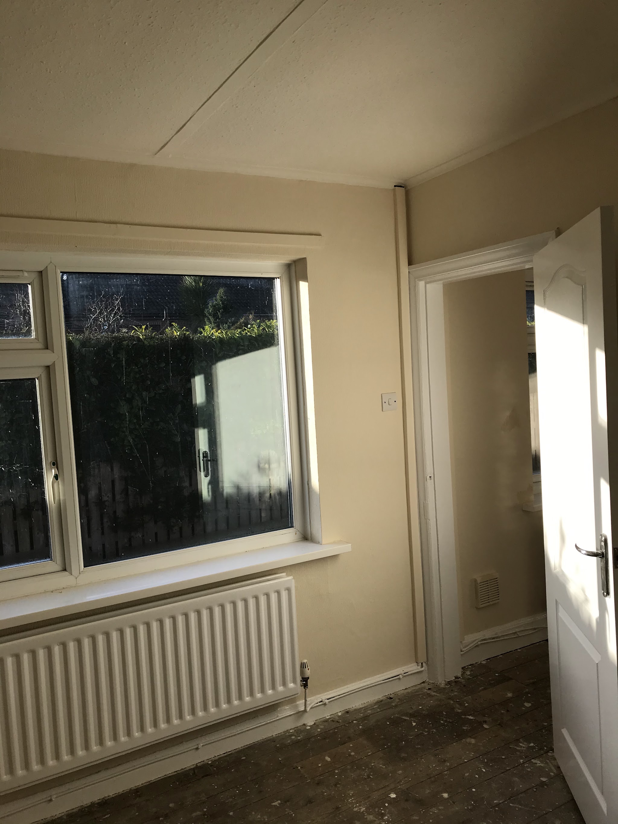 Finished room in cream with a white window frame, radiator and door